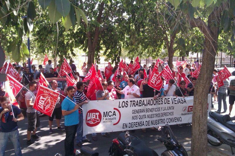Delegados y trabajadores de Veiasa protestan con pancarta y pitos ante la sede central de la empresa, ubicada en La Cartuja.